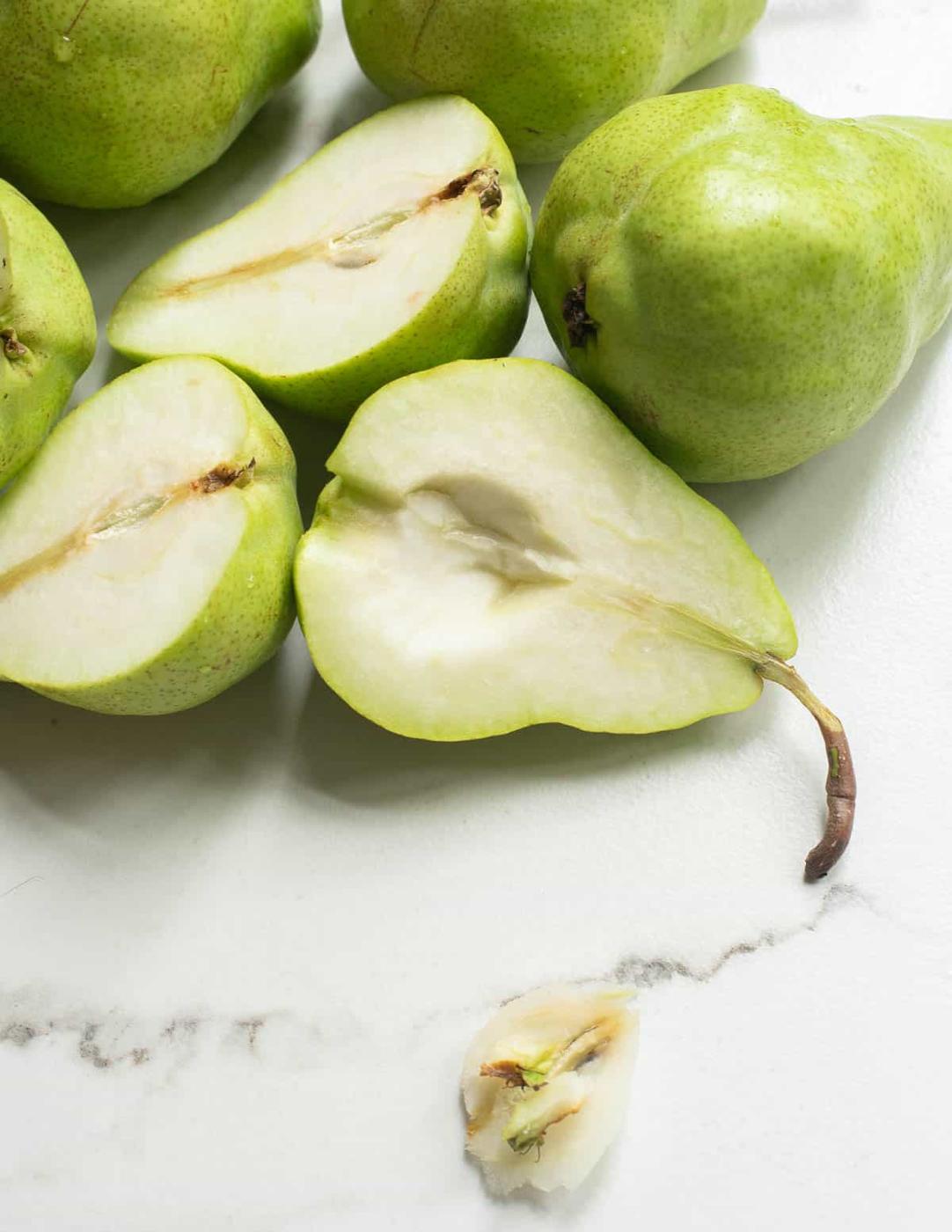 Cored pears in a pile on a white surface.