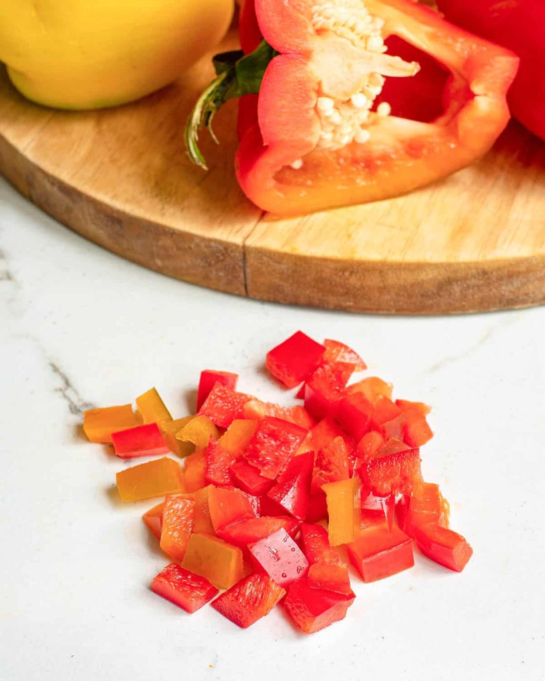 Diced red bell pepper on a white marble surface.