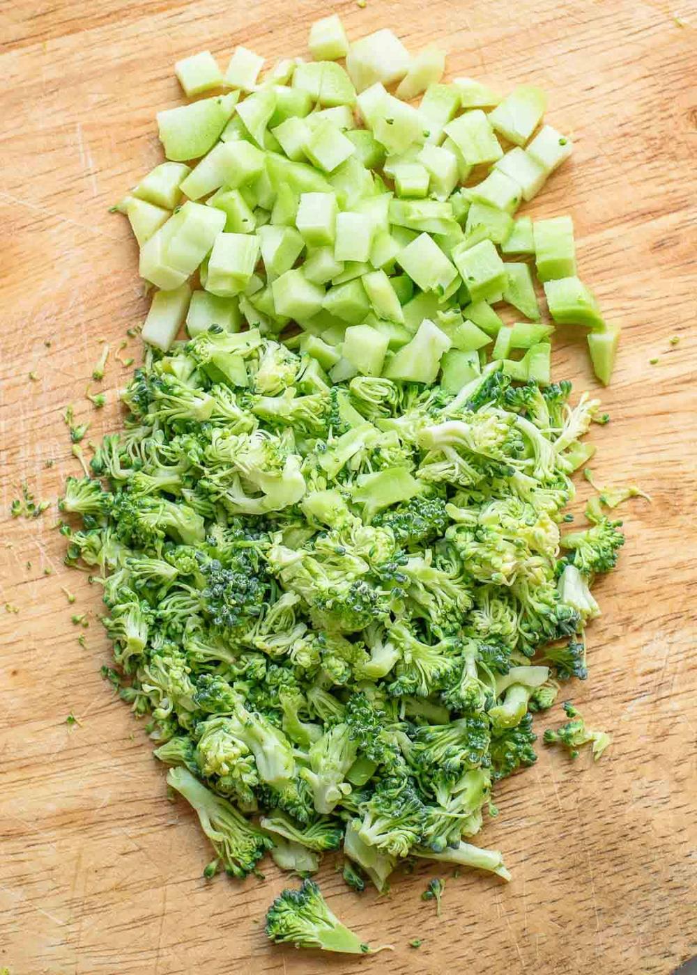 Chopped broccoli stems and florets on a wooden surface.