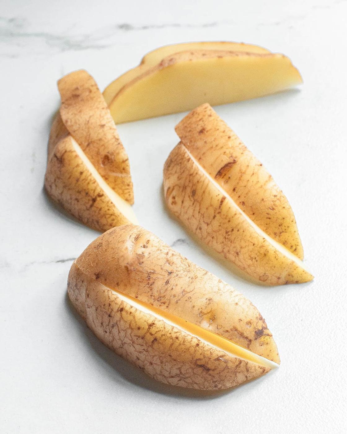 Potato slices on a white marble surface.