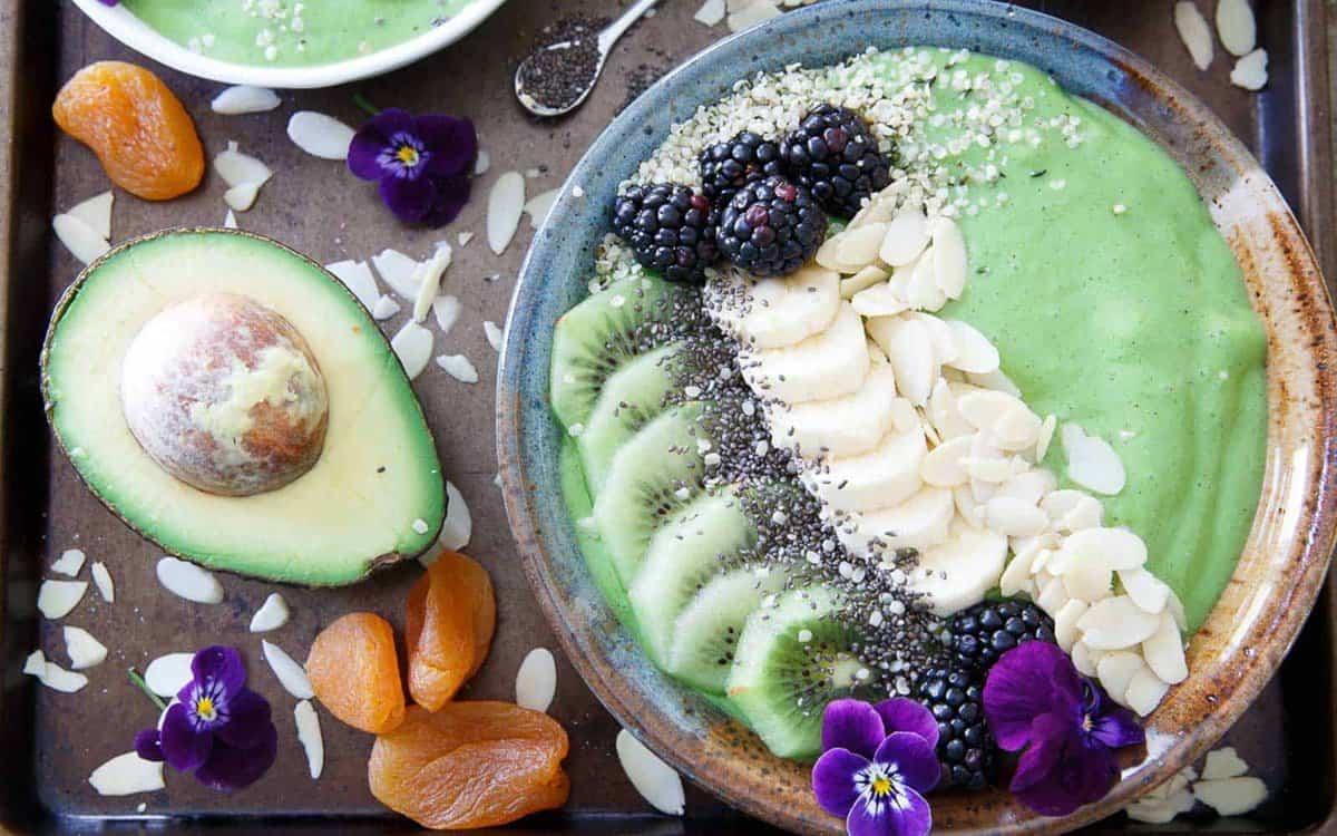 A bowl of green smoothie with blackberries and bananas.
