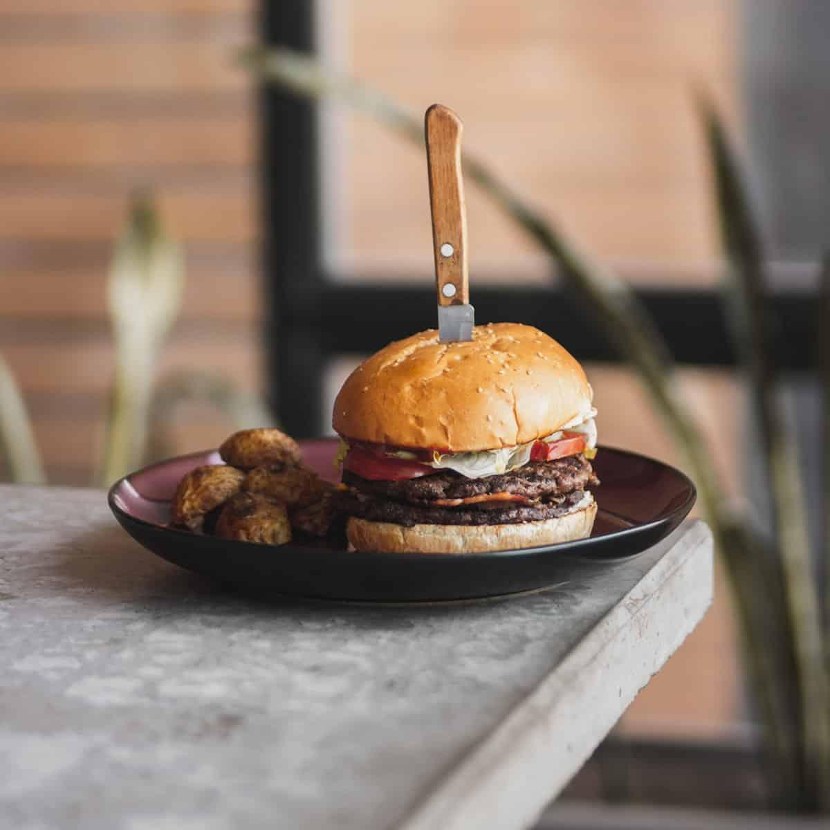 A burger on a plate with a knife on it.