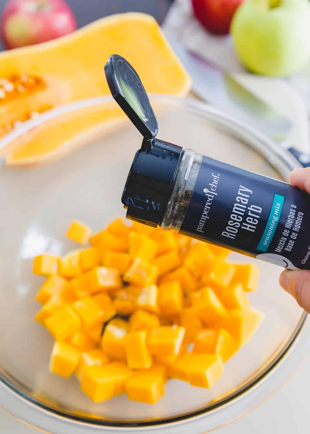 seasoning the butternut squash with salt, pepper and rosemary herbs before roasting to top hummus pizza