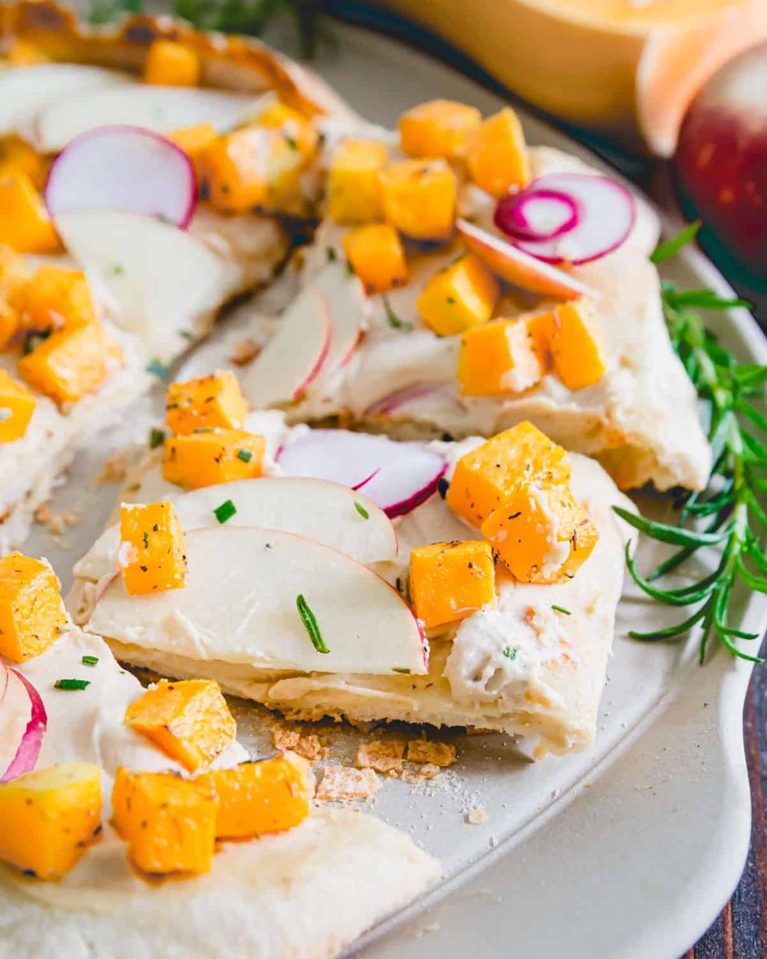 Hummus replaces cheese on this non-traditional fall inspired pizza with rosemary roasted butternut squash, apples and radishes.