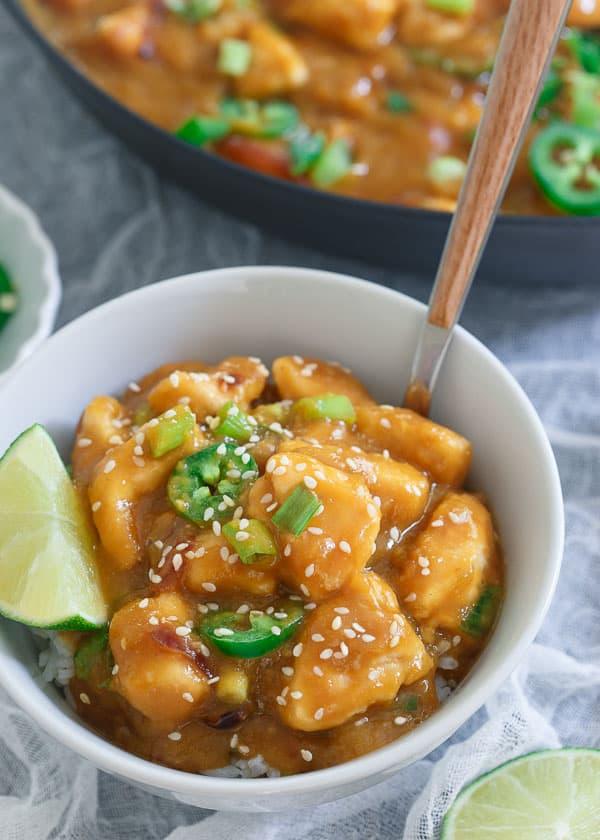 Jalapeño mango chicken in a bowl over rice with a lime wedge.