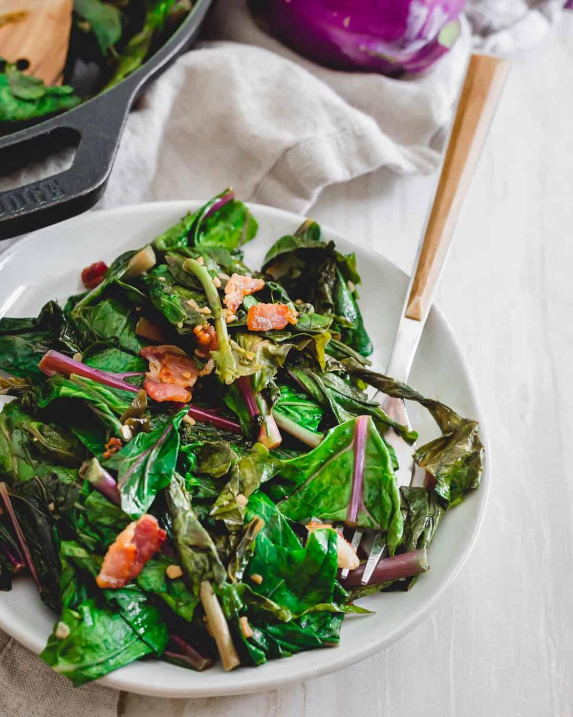 How to cook kohlrabi greens in a skillet with bacon, green onions and garlic.