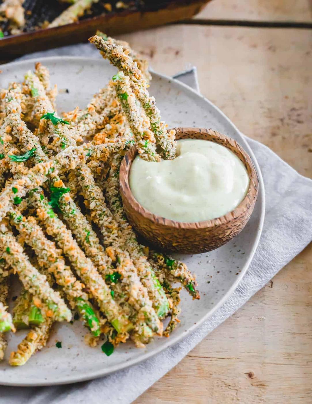 Two asparagus fries in small bowl of dipping sauce.