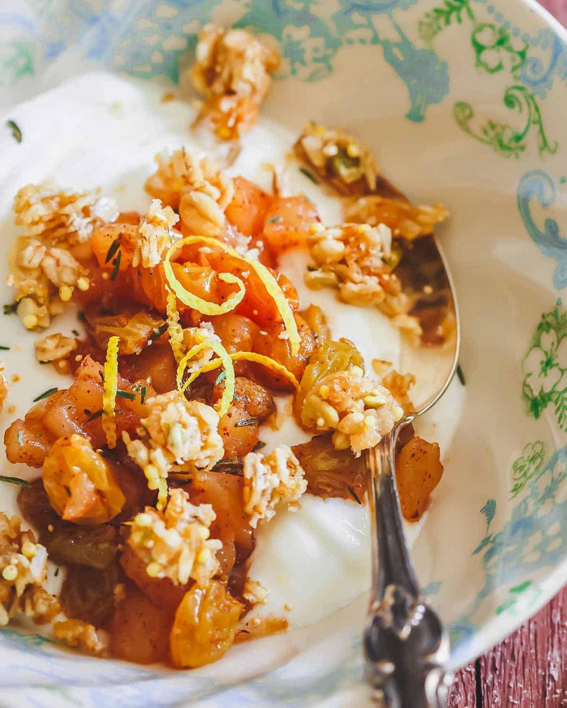 Yogurt bowl with apple compote and granola with a silver spoon.