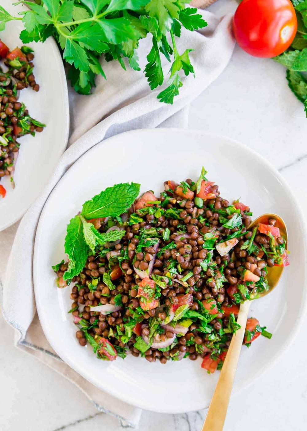Lentil tabbouleh on a white plate with a gold spoon.