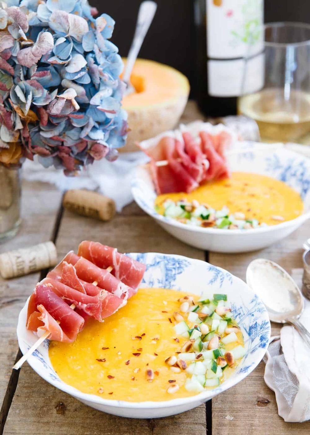 This chilled mango melon soup is garnished with tangy pickled cucumber and prosciutto skewers for a salty, sweet and cool summer dish.