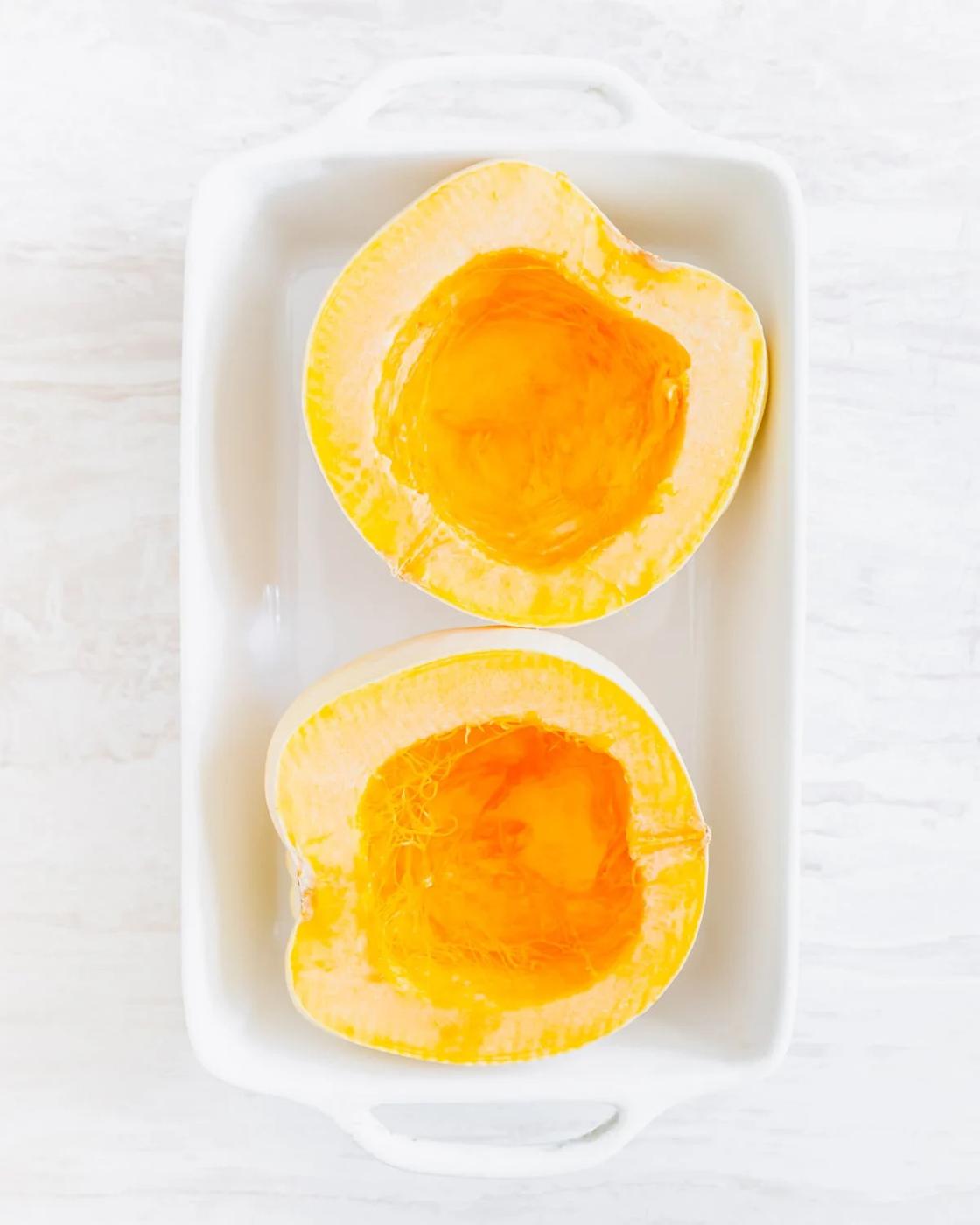 seeded white acorn squash in a baking dish