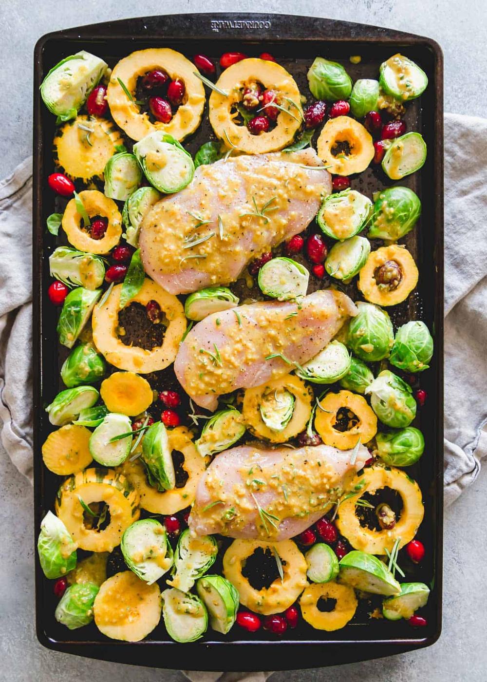 Easy fall dinner made on one pan with chicken breasts, delicata squash, Brussels sprouts, cranberries and a maple mustard sauce with rosemary.