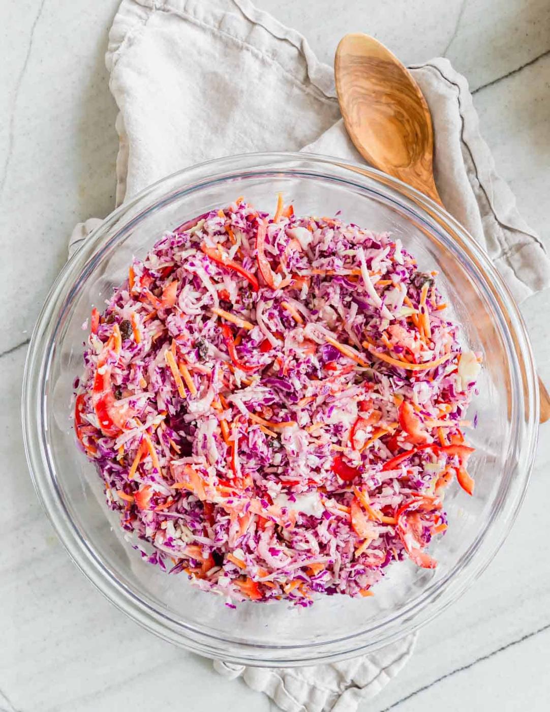 Tossed Irish coleslaw recipe in a bowl with a wooden serving spoon.