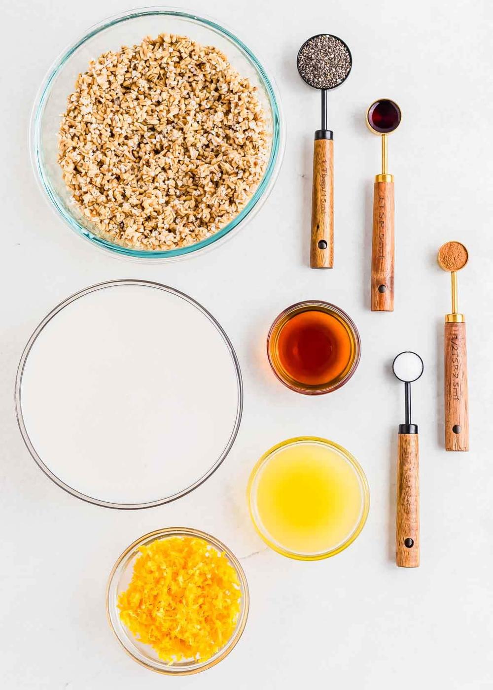 Ingredients in bowls for making overnight steel cut oats including soaked steel cut oats, milk, vanilla, orange zest, orange juice, chia seeds, maple syrup, vanilla, cinnamon and salt.