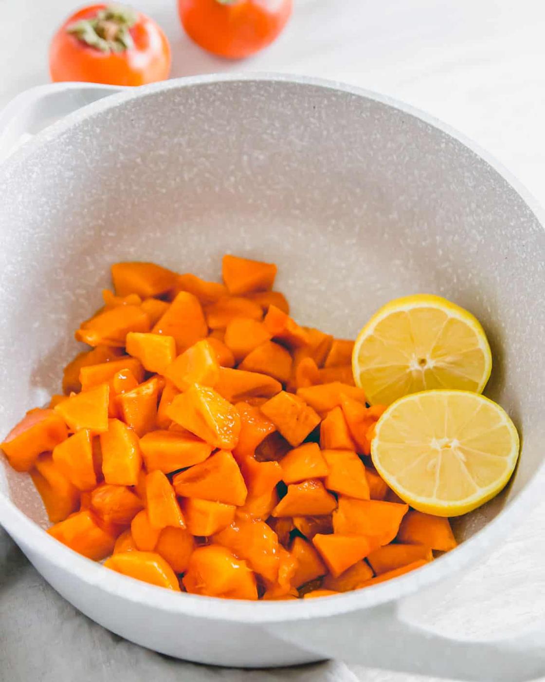Chopped ripe Fuyu persimmons in a pot with lemon for making persimmon jam