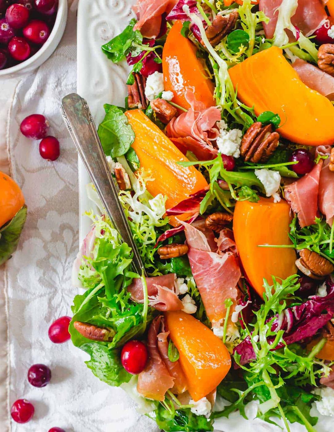 Ripe Hachiya persimmon slices on a bed of dressed greens.