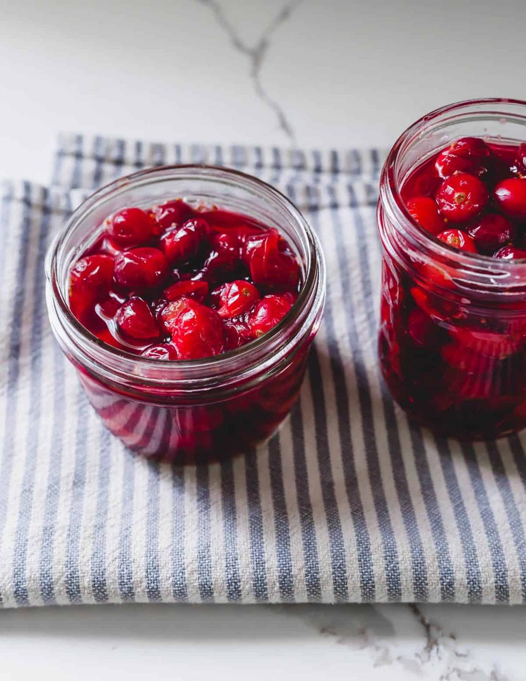 Quick pickled cranberries cooling in brine on kitchen towel.