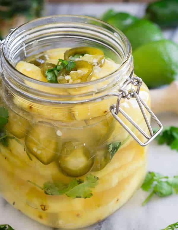 Pickled pineapple with jalapeños in glass jar.
