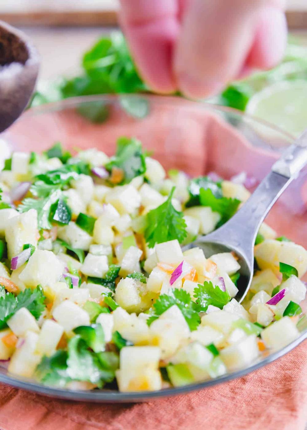 Seasoning pineapple salsa with salt in a bowl.