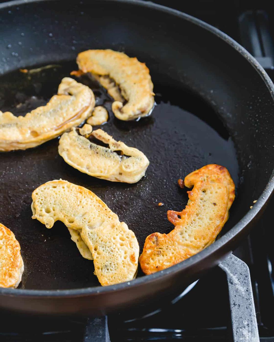 Pan frying battered portobello fries in a cast iron skillet.