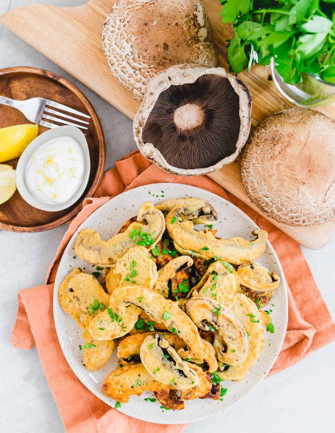 Fried portobello mushrooms on a plate with an orange napkin underneath.