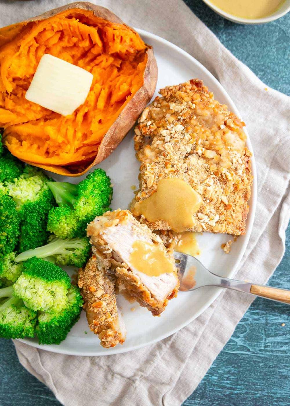 Pretzel pork chops baked in the oven with broccoli and sweet potato make a nutritious and delicious weeknight dinner.