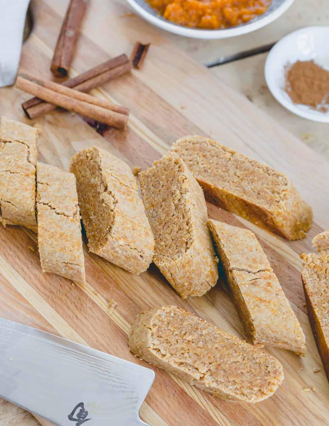 Pumpkin biscotti sliced into cookies after the first bake on a wooden cutting board.