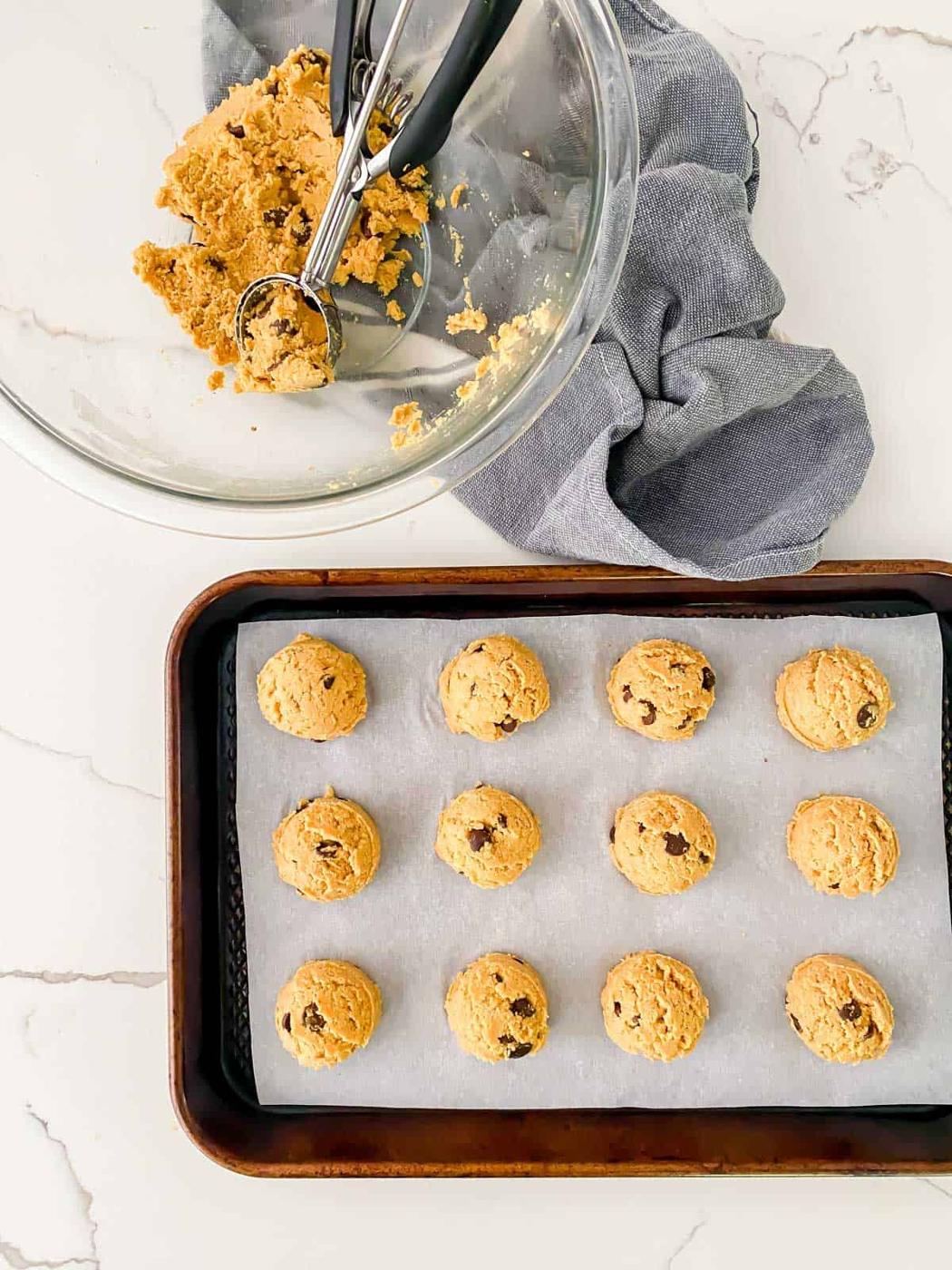 using a cookie dough scoop to shape pumpkin cookie dough into balls