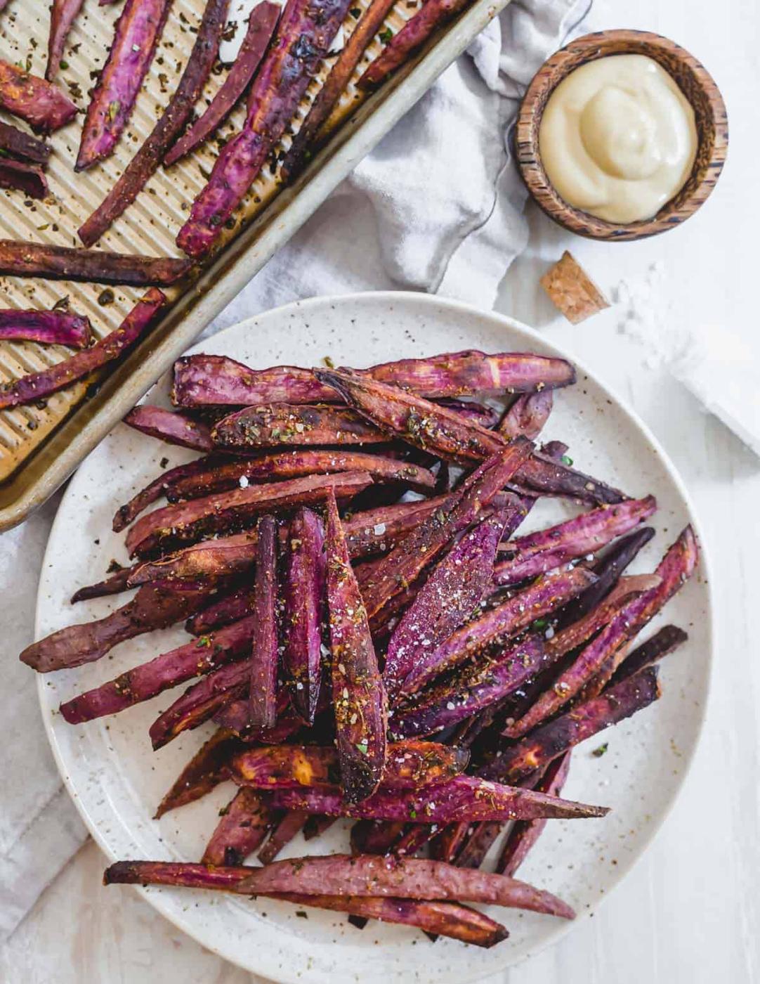 Crispy purple sweet potato fries with herbs and sea salt on a plate.