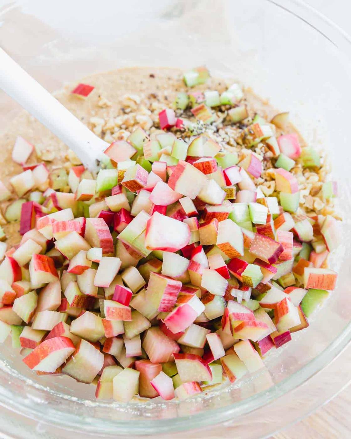 Fresh chopped rhubarb in a glass bowl with batter.