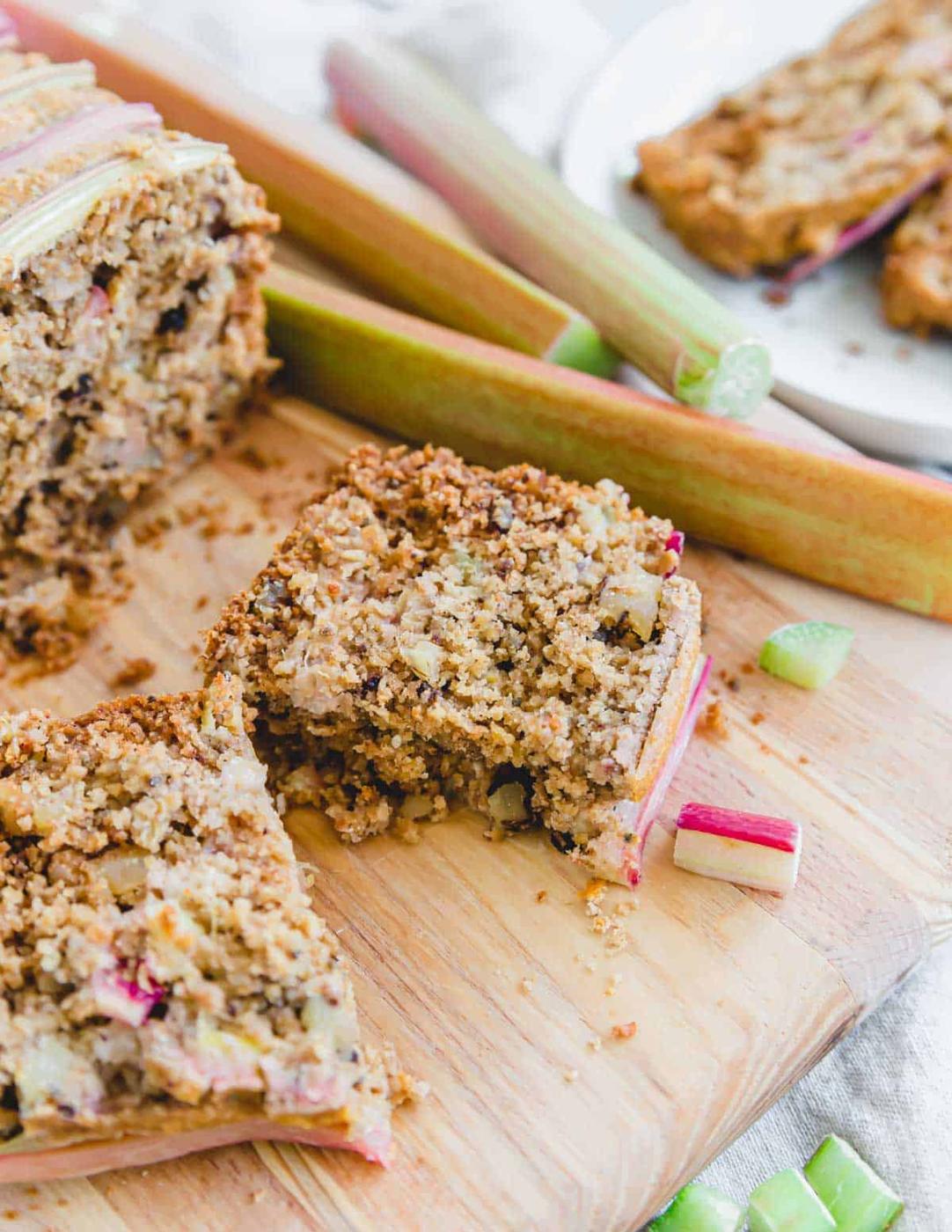 Slice of rhubarb bread cut in half on a cutting board.