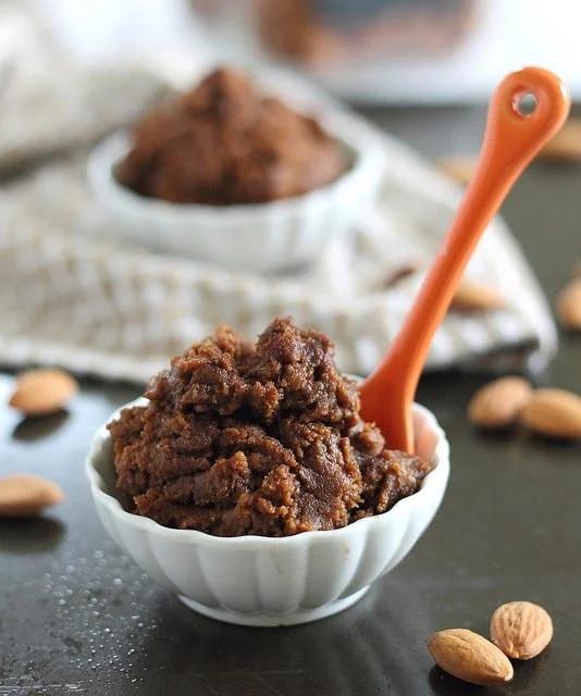 A small white bowl of pumpkin pecan butter with an orange spoon sticking out.