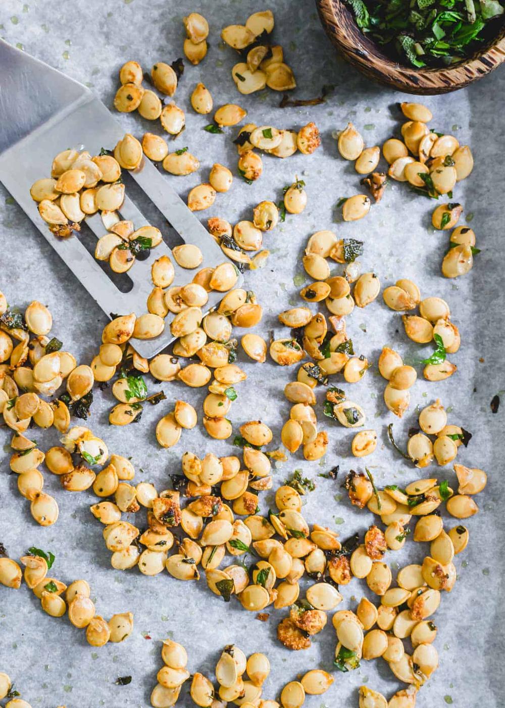 Crispy roasted delicata squash seeds on a baking sheet with spatula.