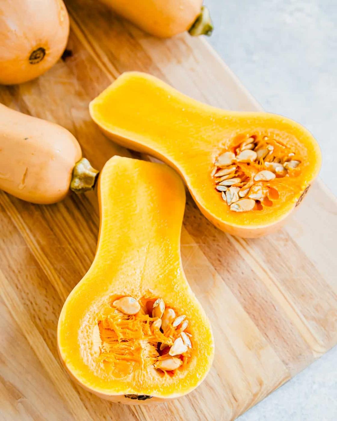 Halved honey patch squash on a cutting board.