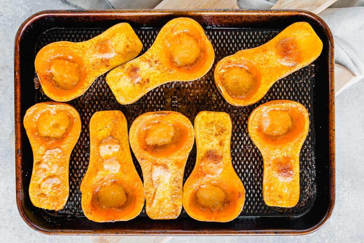 Roasted honey patch squash on a baking sheet with butter and seasoning.