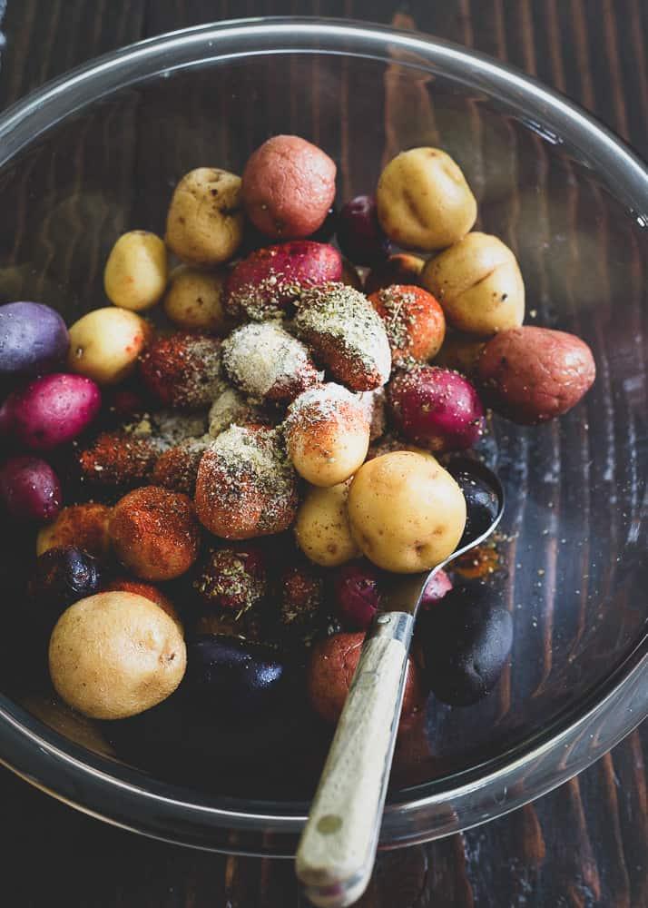 Small red, white and purple potatoes with peri peri spice before being roasted.