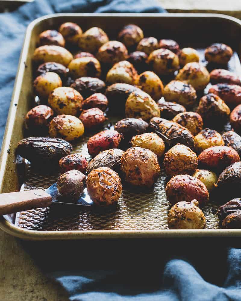 Peri peri potatoes on a baking sheet with a small spatula.