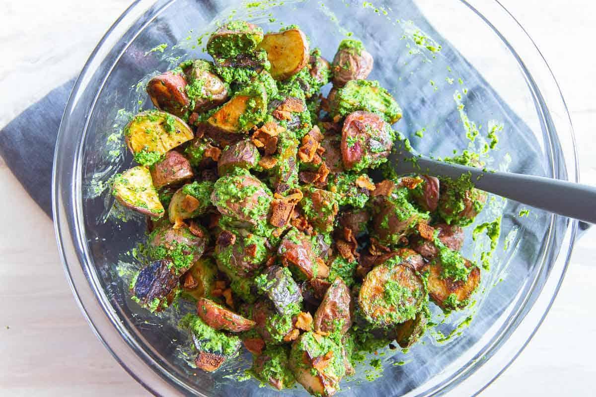Toss roasted potatoes with fresh pesto and crispy bacon for a delicious and easy side dish.