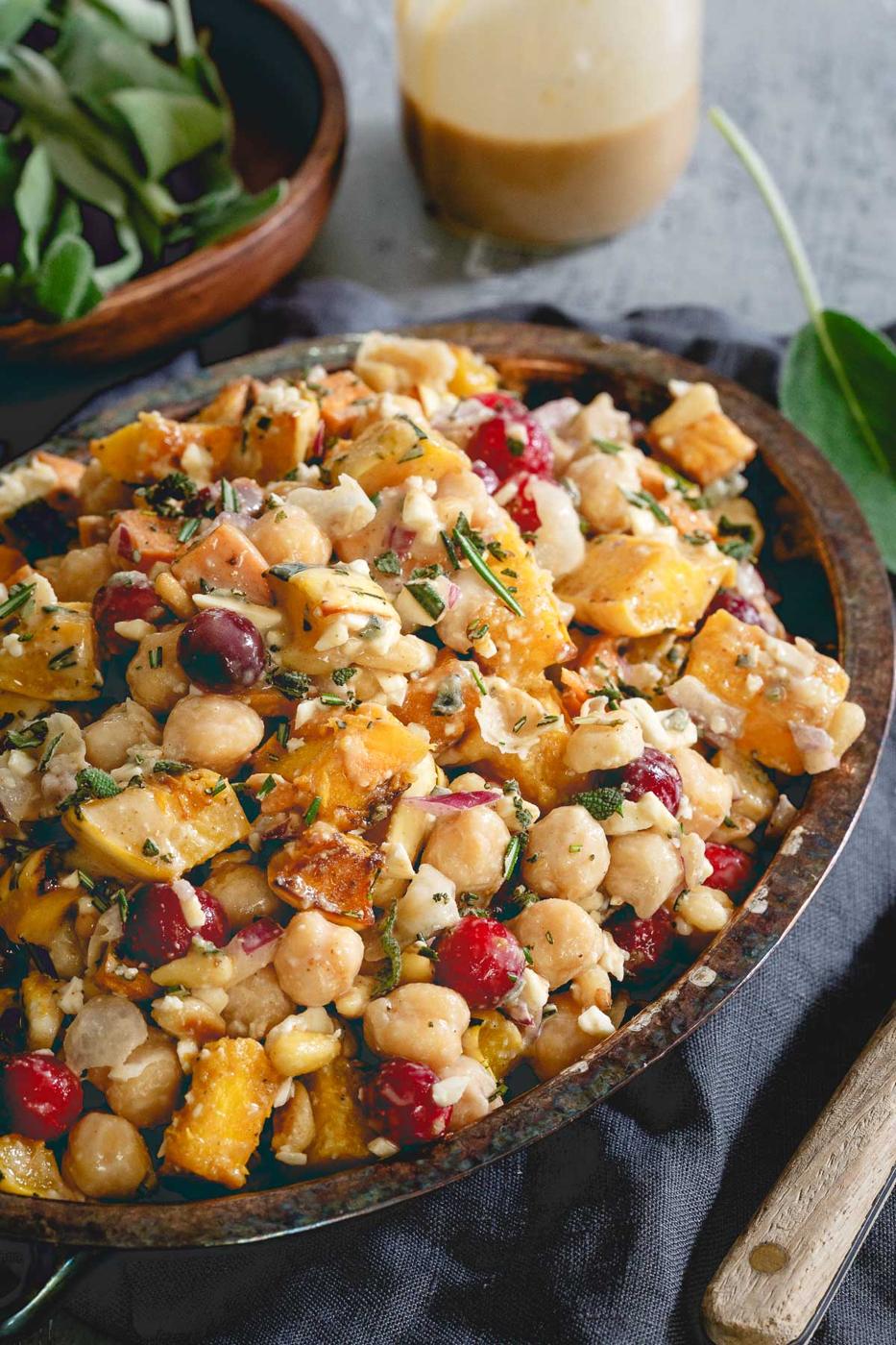 This chickpea fall salad is a hearty vegetarian meal with roasted sweet potatoes, delicata squash, cranberries, feta and a tahini maple dressing.