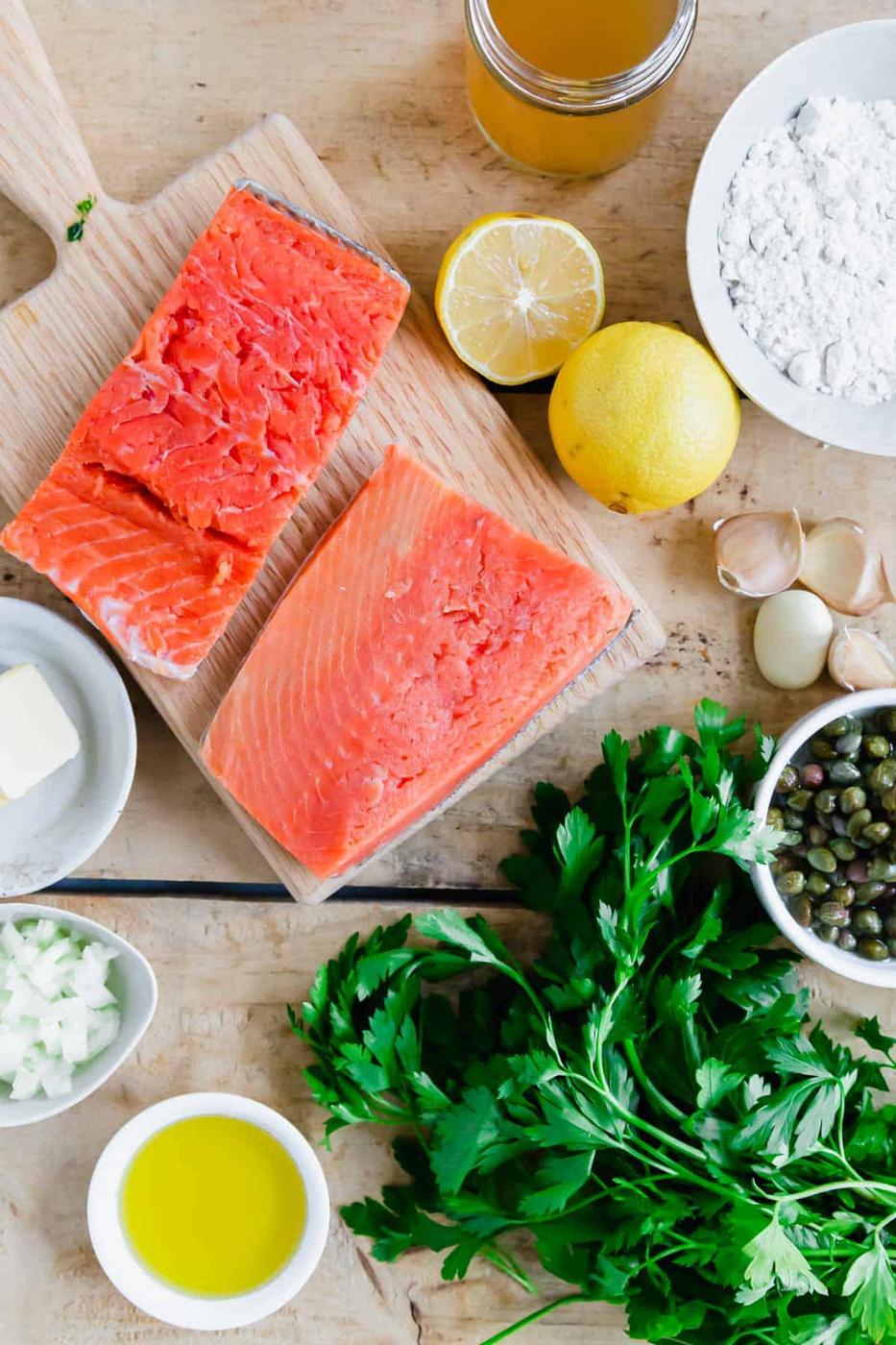 Ingredients to make salmon piccata on wooden surface.