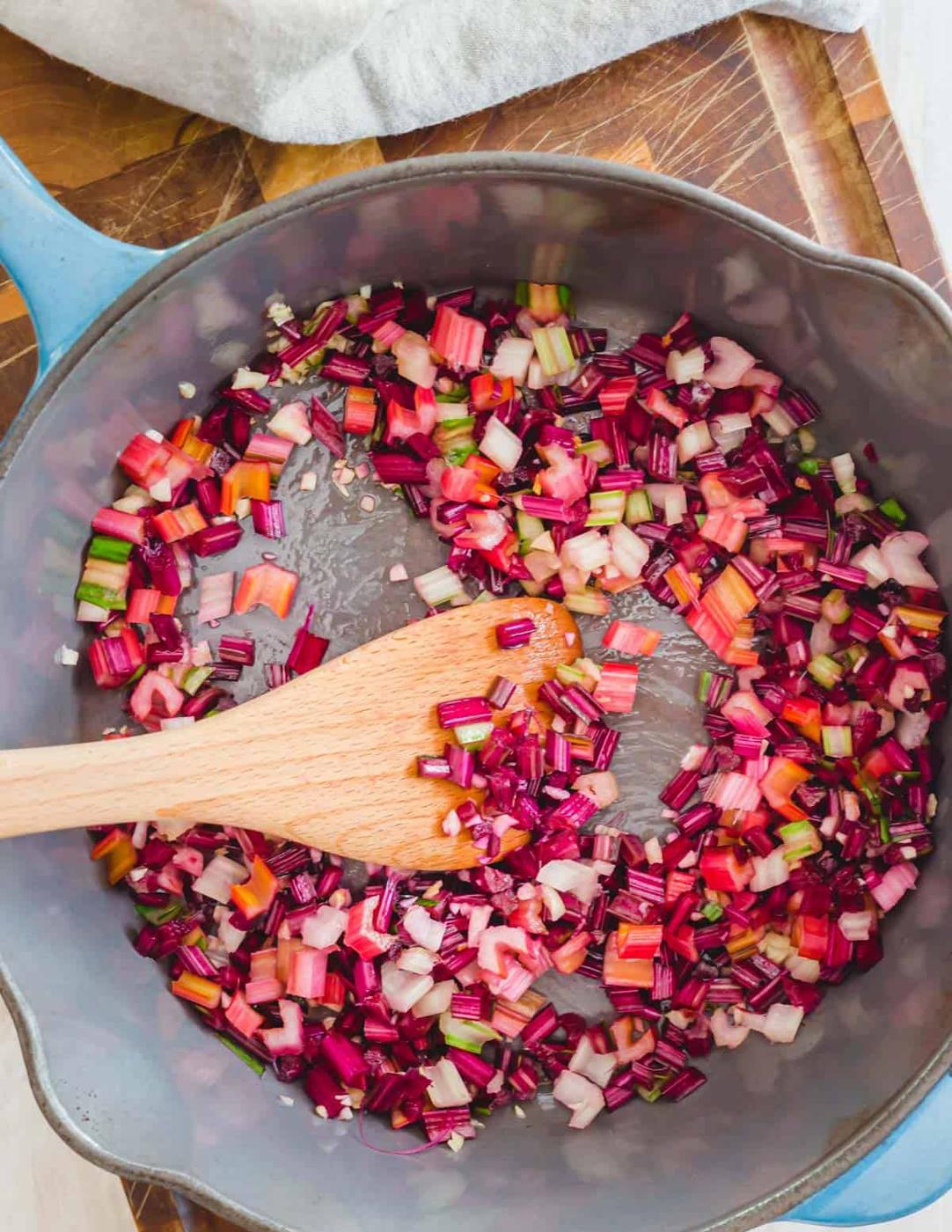 Sautéed Swiss chard and beet greens stems with garlic and olive oil in a pot.