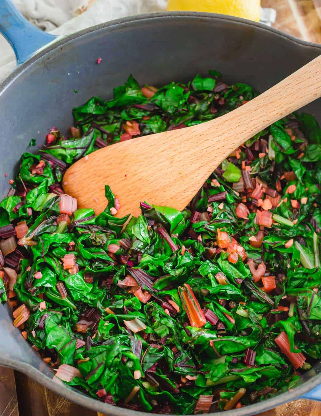 Sautéed greens in a pot with wooden spoon.