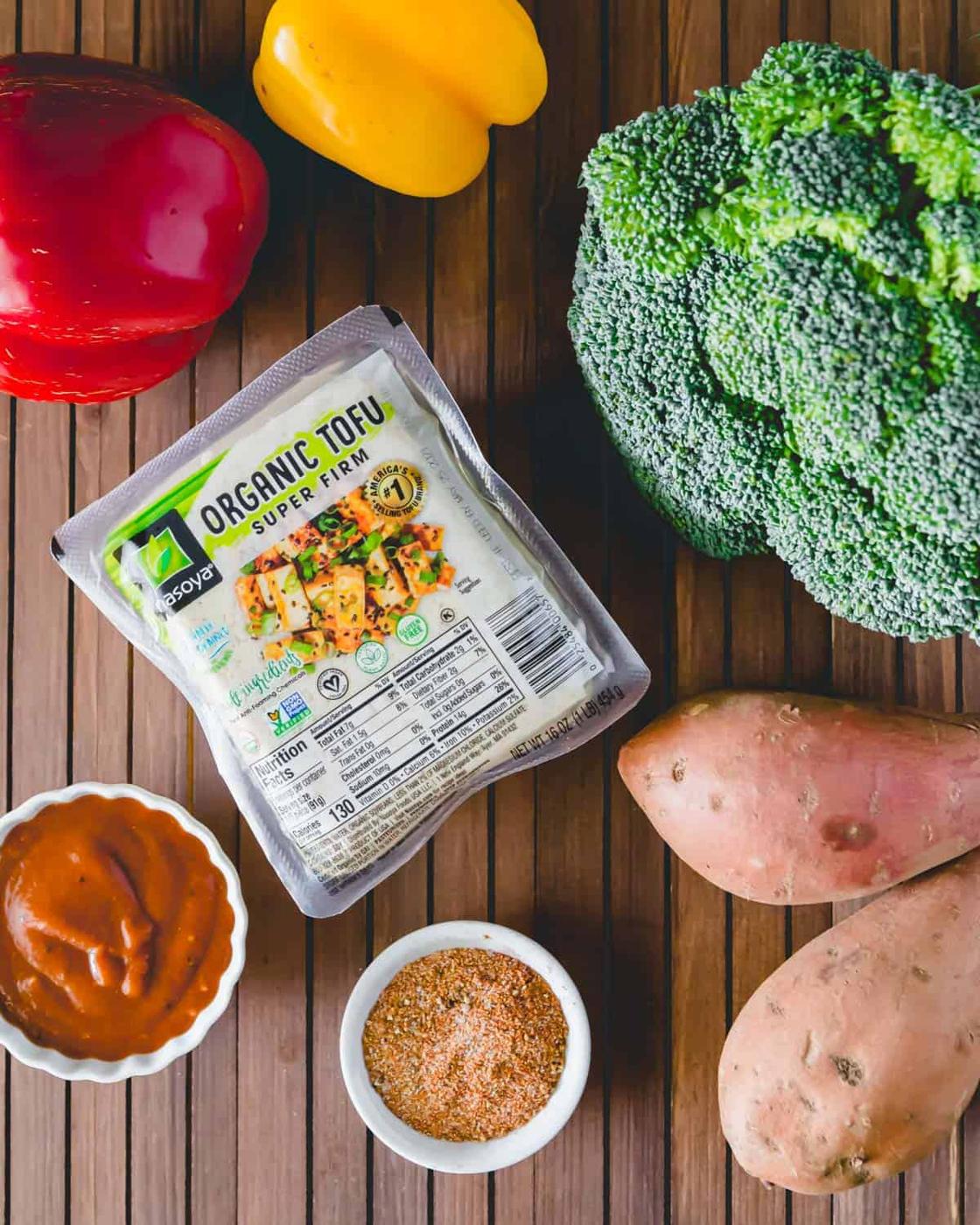 Ingredients to make sheet pan BBQ tofu in the oven: BBQ sauce, organic tofu, broccoli, sweet potato, bell peppers and a dry spice rub.