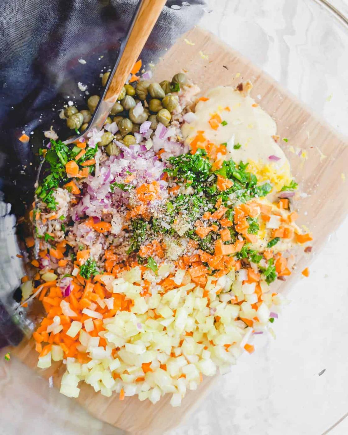 Finely chopped carrots, celery, parsley and red onion with mustard, avocado mayonnaise and lemon in a bowl with mashed sardines.