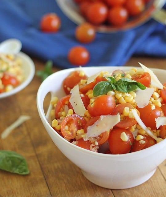 Tomato corn salad in a bowl next to blue towel.