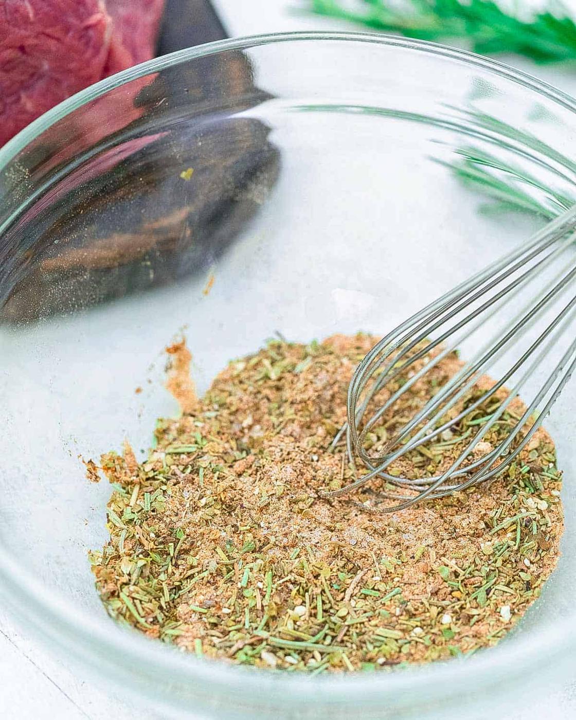 Seasoning blend for a tri-tip roast in a glass bowl with a metal whisk.
