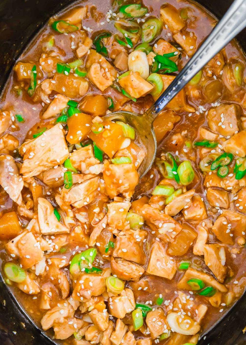 Slow cooker honey garlic chicken in the slow cooker insert with ladle.