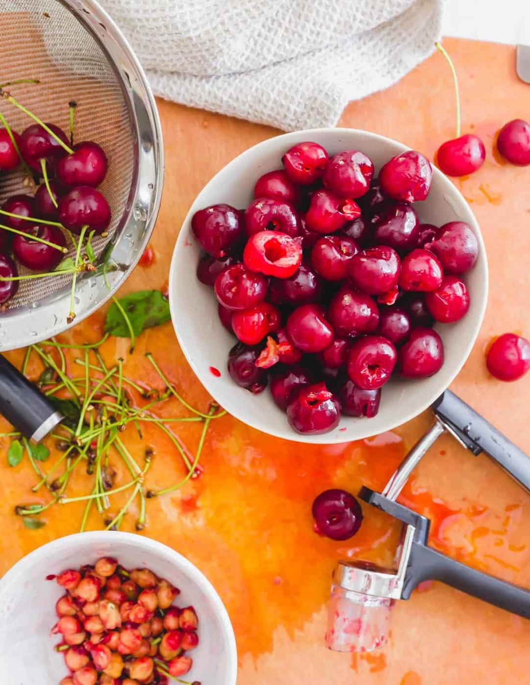 Pitting sour cherries on a cutting board with a cherry pitter.