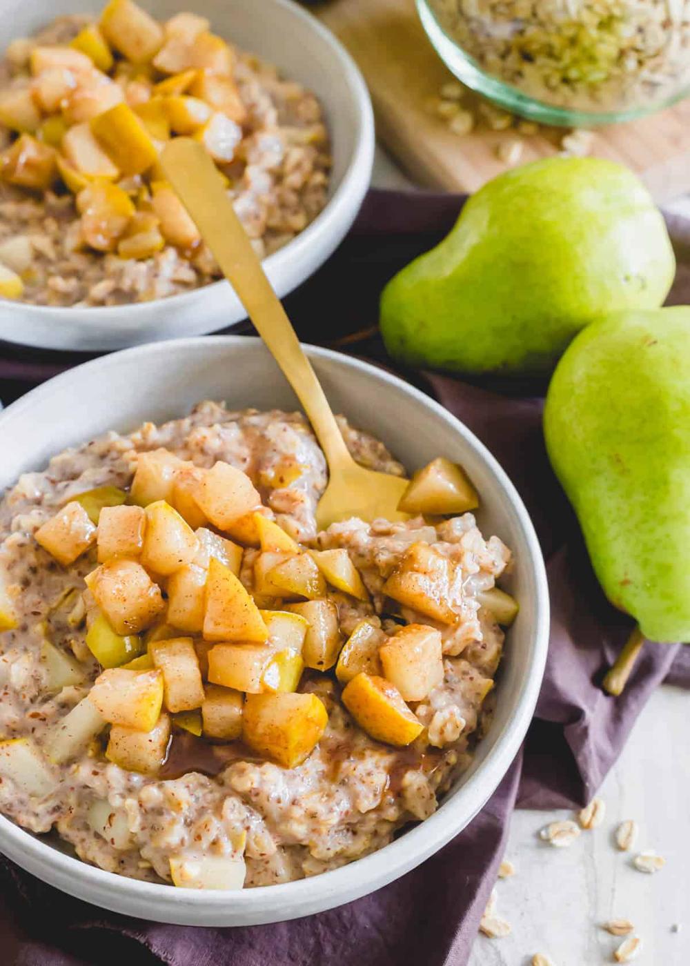 Healthy oatmeal with spiced pear topping in a bowl with a spoon.