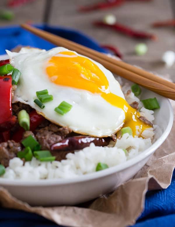 This spicy beef and red pepper rice bowl is cooked with dried red chili peppers and topped with a runny egg.